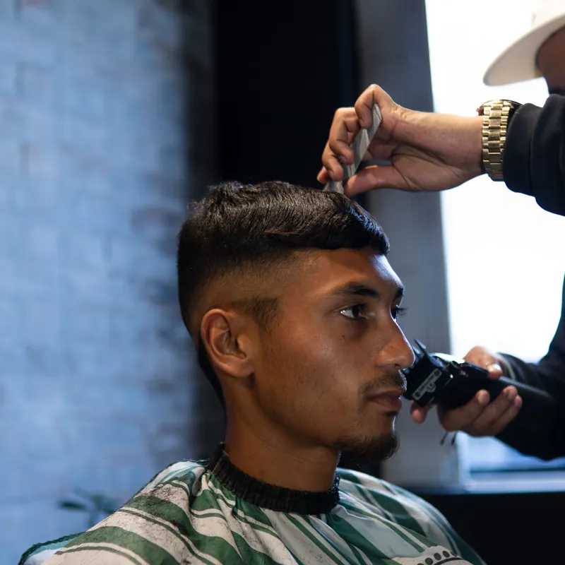 A trimmer squaring the temple of a fresh fade